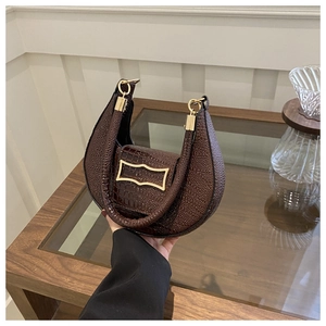 Detailed macro view of dark brown crescent bag with crocodile and lychee leather textures