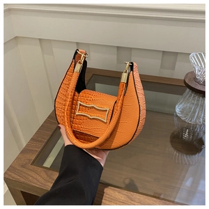 Detail of orange crocodile embossed leather handbag with elegant gold metal buckle