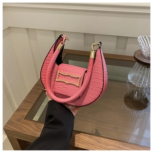 Detail of pink faux crocodile texture on small half-moon bag with golden metal buckle