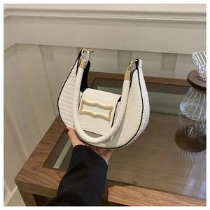Detail of warm white leather dumpling bag featuring lychee texture and gold geometric buckle