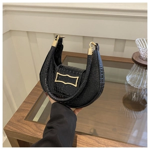 Close-up of black crocodile pattern faux leather underarm bag with gold metal buckle detail