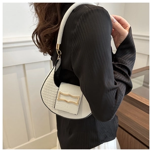 Close-up of white crocodile pattern crescent shoulder bag with gold hardware on model