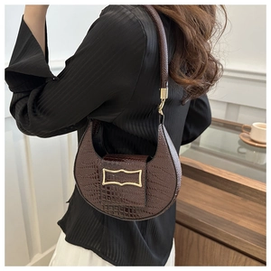 Detail of dark brown crocodile pattern half-moon shoulder bag with gold metal buckle