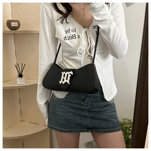 Detail of black underarm bag with silver gothic logo and metallic hardware buckle