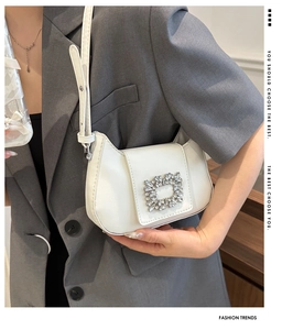 Détail d'un sac à bandoulière blanc en demi-lune avec une boucle carrée en cristal brillant