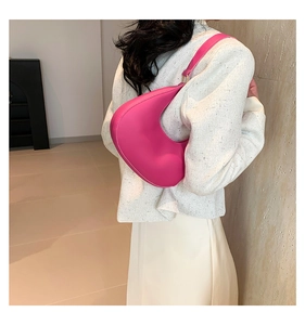 Rose pink crescent shoulder bag shown on model with minimalist interior background