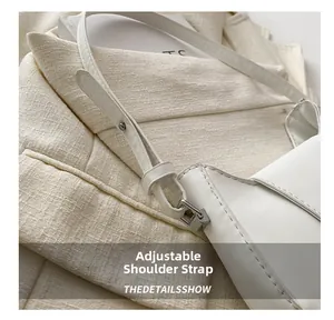 Détail de la bandoulière réglable avec œillets métalliques sur sac à bandoulière blanc