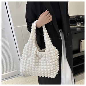 White puffer tote bag with bubble texture shown on model in a stylish minimalist outfit