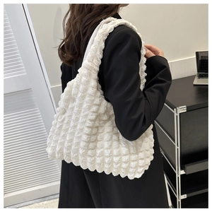 Detail of the white bubble textured shoulder bag showing 3D waffle fabric on the model