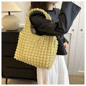 Soft yellow popcorn fabric tote bag with pleated texture shown by model in minimalist room