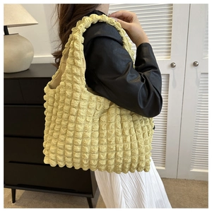 Detail of trendy pale yellow popcorn texture tote bag worn with a chic outfit