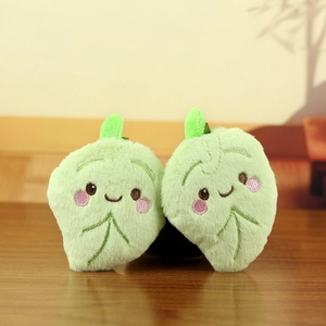 Detailed view of two cute green plush leaf charms with delicate facial embroidery