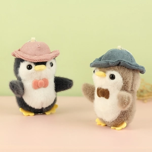 Cute penguin plush keychains with corduroy hats and metal chains on a pastel background