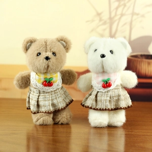 Close-up of brown and white plush bears in plaid dresses on a wooden surface