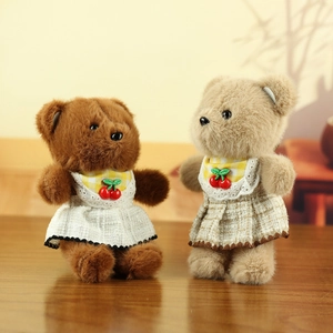 Close-up of cute teddy bears in brown and beige with embroidered dresses and cherry decor
