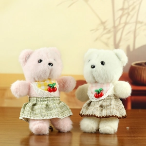 Close-up of cute plush bear charms with plaid bibs and cherry details in soft indoor lighting
