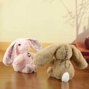 Cute plush bunny pendants with long ears and floral details on a rustic wooden table