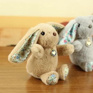 Close-up of plush rabbit charms with floral ear details and golden heart pendant