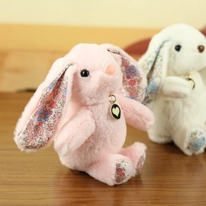 Detailed close-up of plush rabbit charms with floral fabric ears and heart enamel pendants