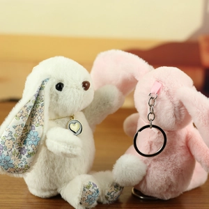 Close-up of plush rabbit keychain with floral inner ears and heart pendant detail