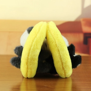 Detail of cute panda plush earmuffs with soft yellow frame on a dark wooden table
