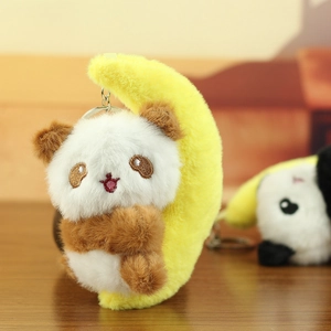 Macro shot of cute plush red panda clinging to a soft yellow moon on a metal keychain
