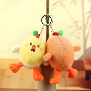 Close-up of yellow and orange plush chick keychains hanging on a natural branch