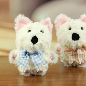 Dettaglio di un cucciolo di peluche con fiocco a scacchi blu e ricamo di zampe rosa