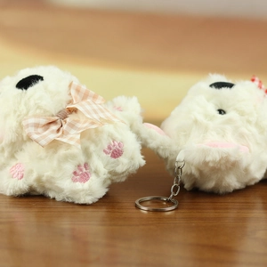 Dettaglio di un portachiavi a forma di cucciolo bianco con ricamo rosa e fiocco a quadri
