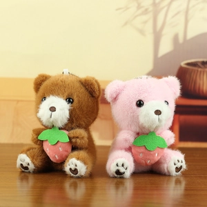 Detailopname van twee pluche teddybeer hangers met aardbeien en zilveren bolletjeskettingen