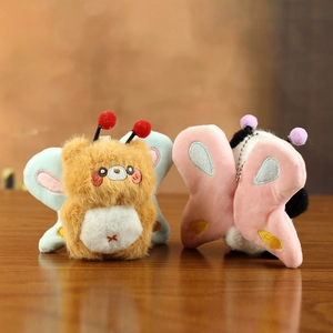 Cute plush bear and panda keychains with butterfly wings on a wooden background