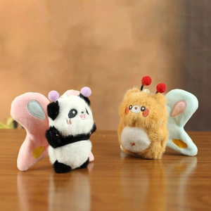 Close-up of plush panda and bear dolls with colorful butterfly wings on a wooden table