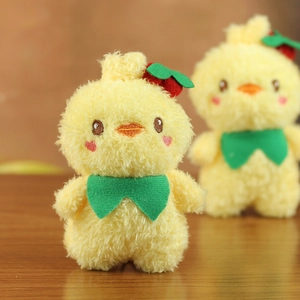 Cute yellow plush duck keychain with strawberry hat and green bow on wooden table