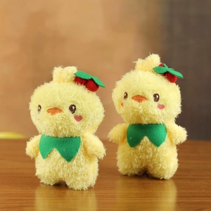 Detail view of plush yellow ducklings with cherry hats and green scarves on wood