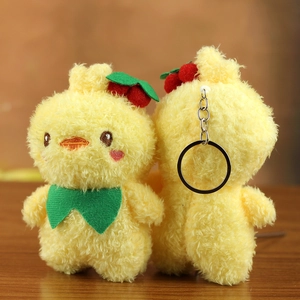 Front and back detail of a yellow plush chick keychain with a red cherry and green bow