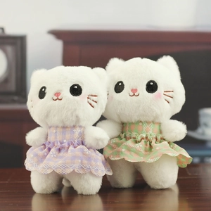 Detailed view of two cute white plush cats in plaid princess dresses on wood