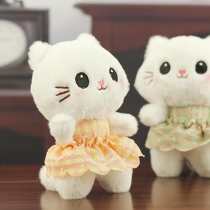 Close-up of cute white plush cats in plaid skirts with intricate facial embroidery