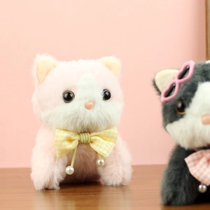 Close-up of cute plush cat toys with yellow plaid bow tie and pearl heart charms