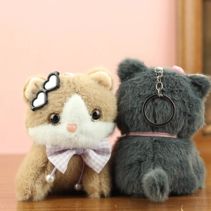 Close-up of plush cat keychain with heart sunglasses and bow tie on wooden stand