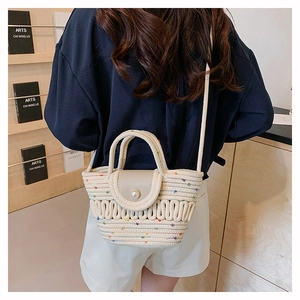 Detail of hand-woven straw tote bag with silk scarf handle and pearl buckle detail