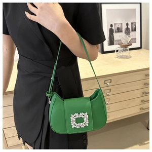 Détail d'un sac selle vert vif avec une boucle luxueuse en strass et bandoulière