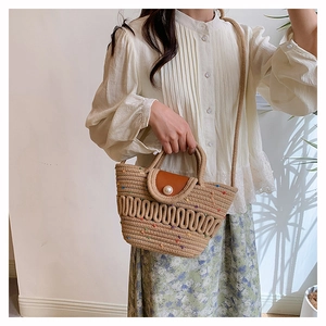 Detail of woven straw bucket bag featuring colorful accents and faux pearl button closure