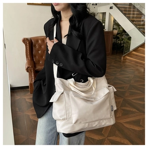 Detail of off-white canvas tote bag with multiple utility pockets and fashion label