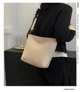 Detailed view of beige woven tote bag with a geometric pattern fabric shoulder strap