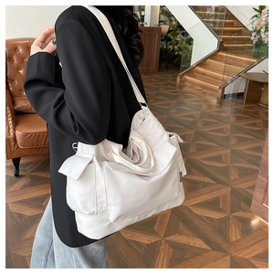 Close-up of off-white tote bag with multiple side pockets and adjustable strap details