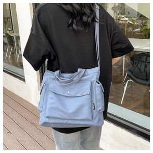 Detail showing the light blue multi-pocket tote bag with adjustable shoulder strap and handles
