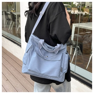 Detail view of light blue large capacity tote bag with adjustable strap and front pockets