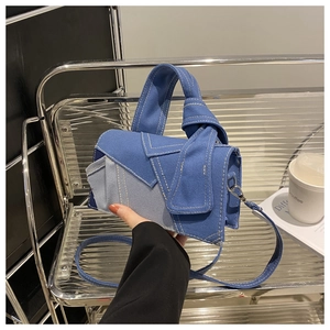 Detail of blue denim patchwork handbag with contrast stitching and knotted handle detail