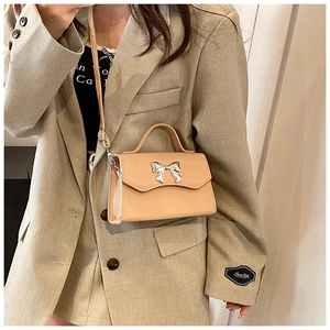 Mini borsa a tracolla in pelle beige con fiocco argento indossata da modella