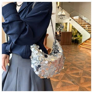 Close-up of sparkling silver sequin crescent hobo bag with sleek metal chain strap